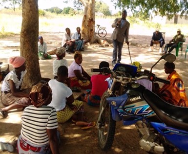 A man with a physical impairment conducts a disability awareness training outside under a tree in mozambique