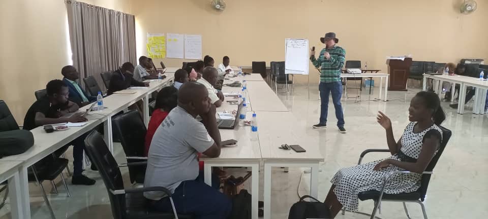 A group of young people with disabilities sitting in a training and listening to a man with Albinism speak