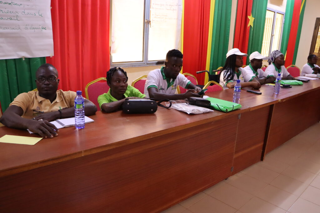 7 young people with disabilities are sitting on a pannel. IN the background you see curtains in the colors of the Burkina Faso flag.